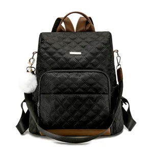 Sac à dos matelassé noir élégant pour femme avec détails en cuir marron et pompon duveteux.