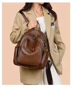 Detail view of stylish brown leather multi-functional backpack with zipper pockets and tassels.