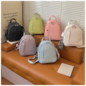 Vue détaillée de plusieurs mini sacs à dos en cuir aux couleurs variées sur canapé.