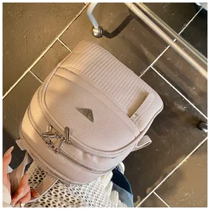 Detailed view of women PU leather backpack with front zipper pocket and triangle metal badge.