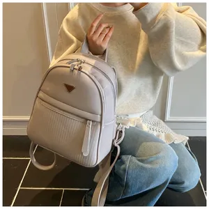 Detailed view of the stylish grey PU leather backpack, highlighting metal triangle accent.