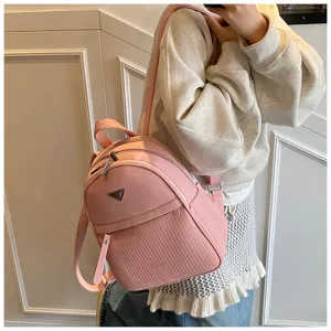 Pink PU leather women's backpack detail showcasing zipper pockets and classic triangle badge design.