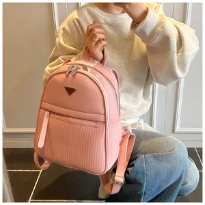 Close-up of a chic pink PU leather backpack with front pocket and metal hardware for women.