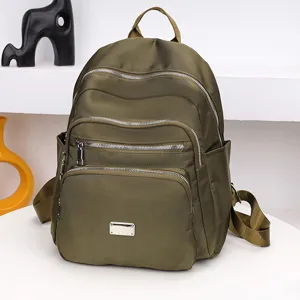 Detailaufnahme des olivgrünen Nylon-Rucksacks mit Front-Metallplatte und Reißverschlüssen.