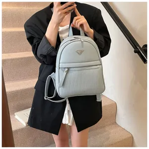 Detail shot of a light blue PU leather backpack featuring a chic front triangle plaque.