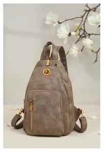 Primer plano de un elegante bolso de pecho multifuncional para mujer en gris con herrajes dorados.