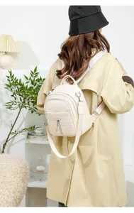 Detailed view of women casual beige PU backpack worn by model in clean indoor studio scene.