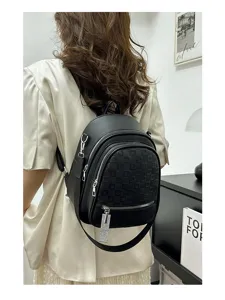 Detail view of stylish black faux leather mini backpack with embossed pocket and rhinestone charm.