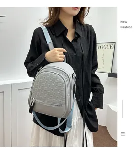 Detail shot of a stylish grey women backpack with debossed pattern and blue straps for casual use.