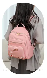 Pink fashion backpack detail featuring elegant floral embroidery and stylish front pocket design.