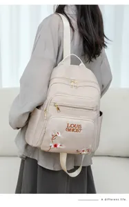 Detailed view of beige fashion casual backpack with floral embroidery and front design.