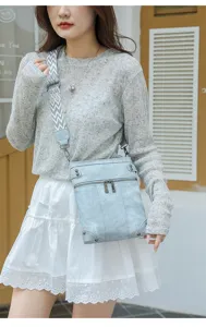 Close-up view of light blue crossbody bag with patterned wide strap and multi-pockets.
