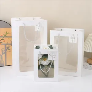 Detail van de papieren cadeautas met transparant venster en elegante handgreep.