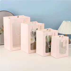 Roze papieren cadeautassen met transparante vensters in meerdere maten voor bloemen en cadeaus.