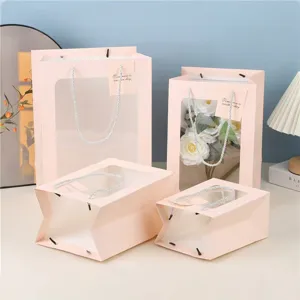 Roze papieren cadeauzakjes met doorzichtig venster voor bloemboeketten en feestelijke gelegenheden.
