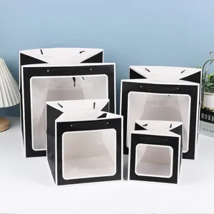 Vue détaillée de sacs cadeaux en papier noir et blanc avec fenêtre transparente et poignée.