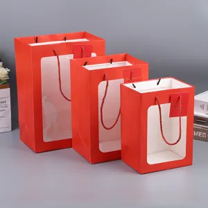 Red paper gift bags with transparent window, handles and tags for flower and party packaging.