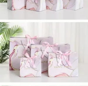 Detailed view of luxury paper gift bags with pink silk ribbon bows and elegant marble design.