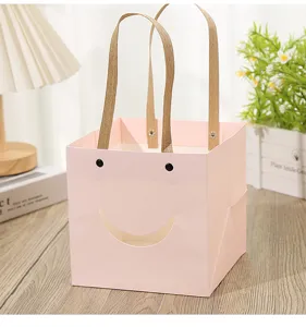 Close-up of the pink square gift bag with cute cutout smile face and sturdy fabric handles.