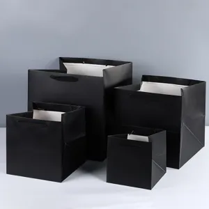 Detailed view of thick black square gift paper bags with wide bottom for retail and bakery packaging.