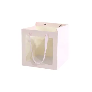 Bolsa de regalo de papel rosa con ventana transparente y asa de cinta para tarta o fiesta.