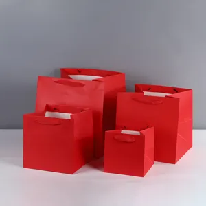 Detail view of thickened red square paper gift bags with wide bottom and ribbon handles.
