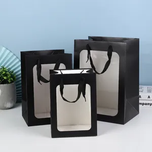Zwarte papieren cadeauzakjes met doorzichtig venster en lint handgrepen voor bloemen en cadeaus.