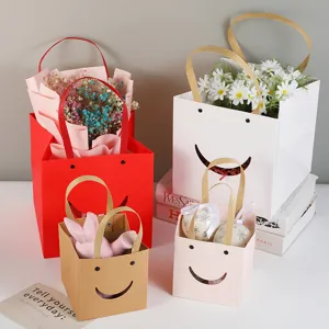 Leuke papieren cadeautasjes met glimlach gezicht en handvatten, ideaal voor bloemen en feesten.