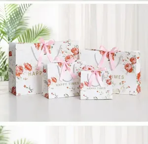 Detailed view of floral paper gift bags with pink ribbon bows, elegant packaging for presents.