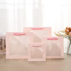 Vierkante roze papieren geschenkzak met doorzichtig venster en lint voor bloemen en taarten.