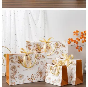 Sacs cadeaux en papier à fleurs dorées avec rubans pour emballage de fête élégant.