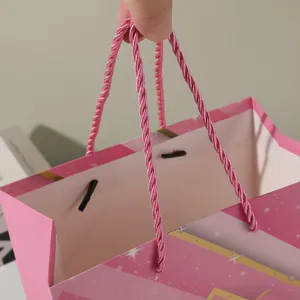 Close-up detail of a pink gift paper bag with delicate handles and star print design.