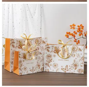 Vue détaillée du sac cadeau à fleurs dorées avec nœud ruban, emballage papier élégant pour fêtes.