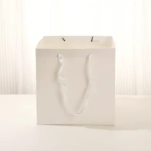 Sac cadeau en papier blanc carré simple avec poignées pour fêtes et mariages élégants.