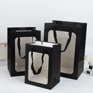 Zwarte papieren cadeauzakjes met doorzichtig venster en handvatten, ideaal voor bloemen.