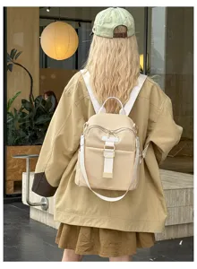 Stylish women's canvas travel backpack, detailed back view showing white straps and metal buckles.