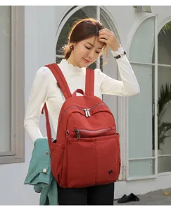 Detailed view of the red nylon backpack showcasing front zipper pockets and durable shoulder straps.