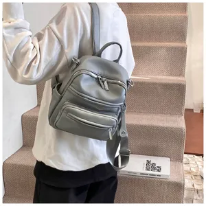 Detailed view of casual grey leather backpack showcasing multi-pocket design and zipper details.