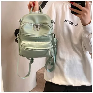 Detailed view of a stylish light green PU leather mini backpack with metal zippers.