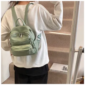 Detailed view of the light green mini leather backpack showcasing multi-pocket zippers and straps.
