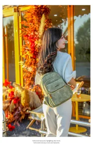 Detailed view of the stylish vintage green suede backpack worn outdoors in an autumn setting.