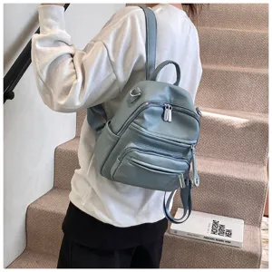 Close-up detail of the stylish light blue leather backpack with multiple zipper pockets.
