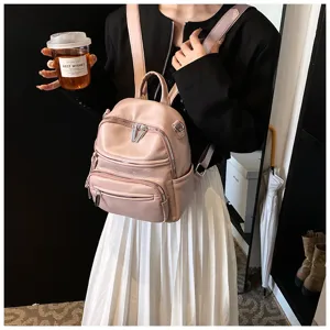 Detail view of the stylish pink leather backpack featuring multiple zip compartments.