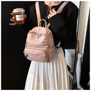 Details showcasing the stylish pink PU leather backpack with multiple front zippered pockets.