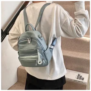 Detail view of stylish light blue women leather backpack worn on model in indoor scene.