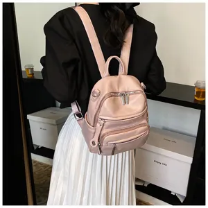 Detailed shot of a pink leather women backpack with multiple zippers and comfortable straps.