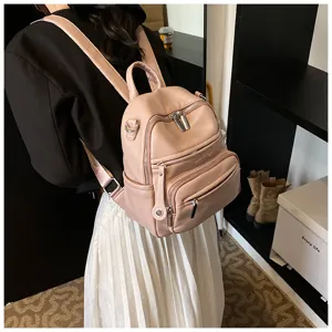 Detail shot of a stylish pink leather backpack worn by a model, showing texture and design.