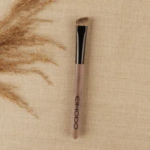 Angled eyebrow makeup brush with wood grain handle and fine bristles for precise definition.