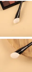 Detailed view of the premium makeup brush with soft white wool bristles and sleek black handle.