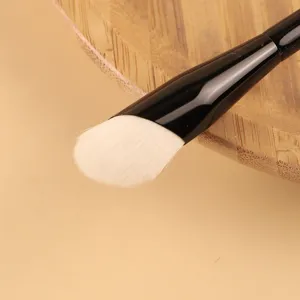 Professional white wool foundation brush with glossy black handle for makeup application.